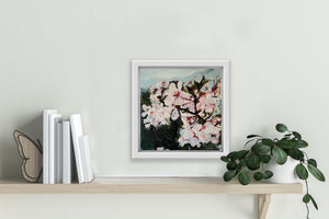 A painting of wild plum blossoms hangs above a shelf.